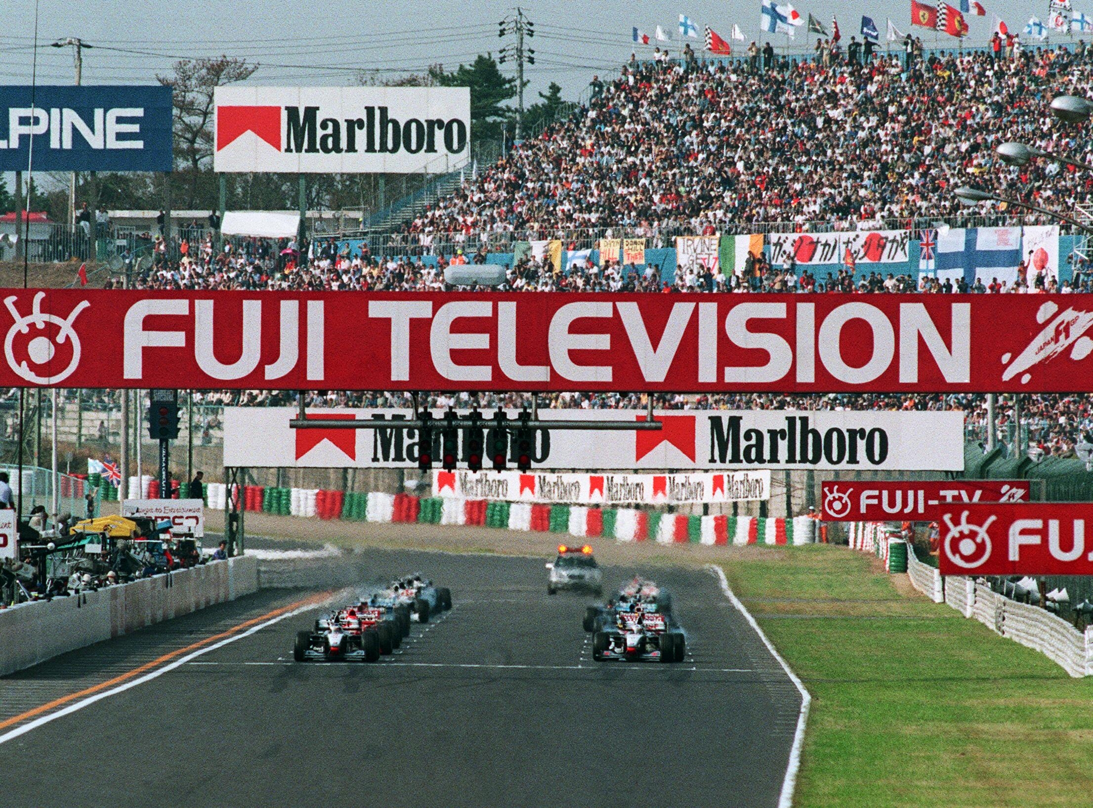 フジテレビのロゴが掲げられた1998年のF1日本GP決勝のスタートライン（三重・鈴鹿サーキット）＝時事