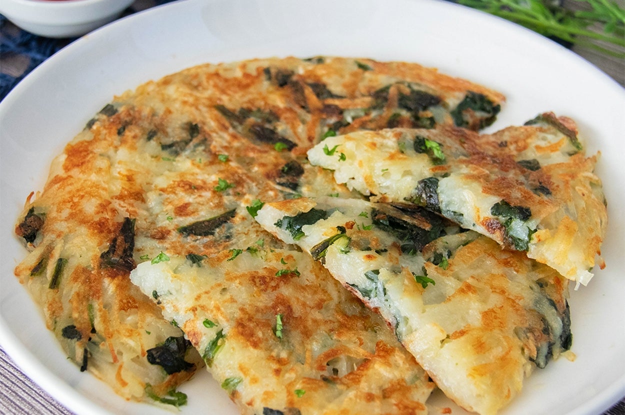 ほうれん草とじゃがいものガレットが白い皿に盛られている。背景にトマトケチャップが添えられている。