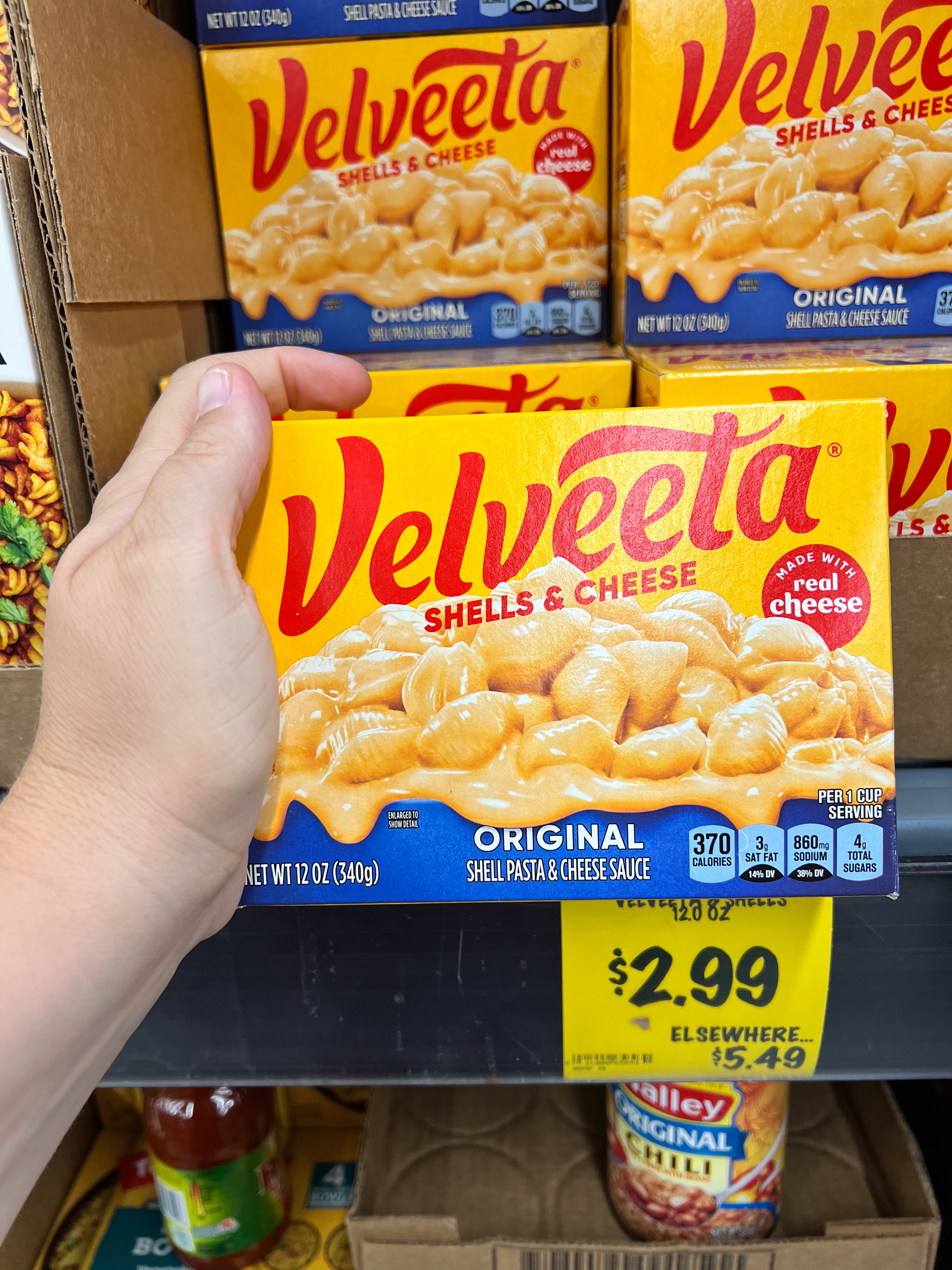 Velveeta Shells & Cheese container held successful hand, highlighting creamy pasta representation connected packaging and a merchantability terms of $2.99 below