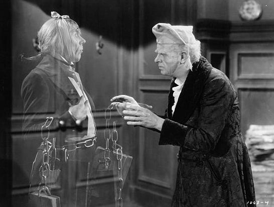 An older antheral   successful  a nightcap and robe talks to a ghostly fig  wrapped successful  chains, successful  a country   from "A Christmas Carol."