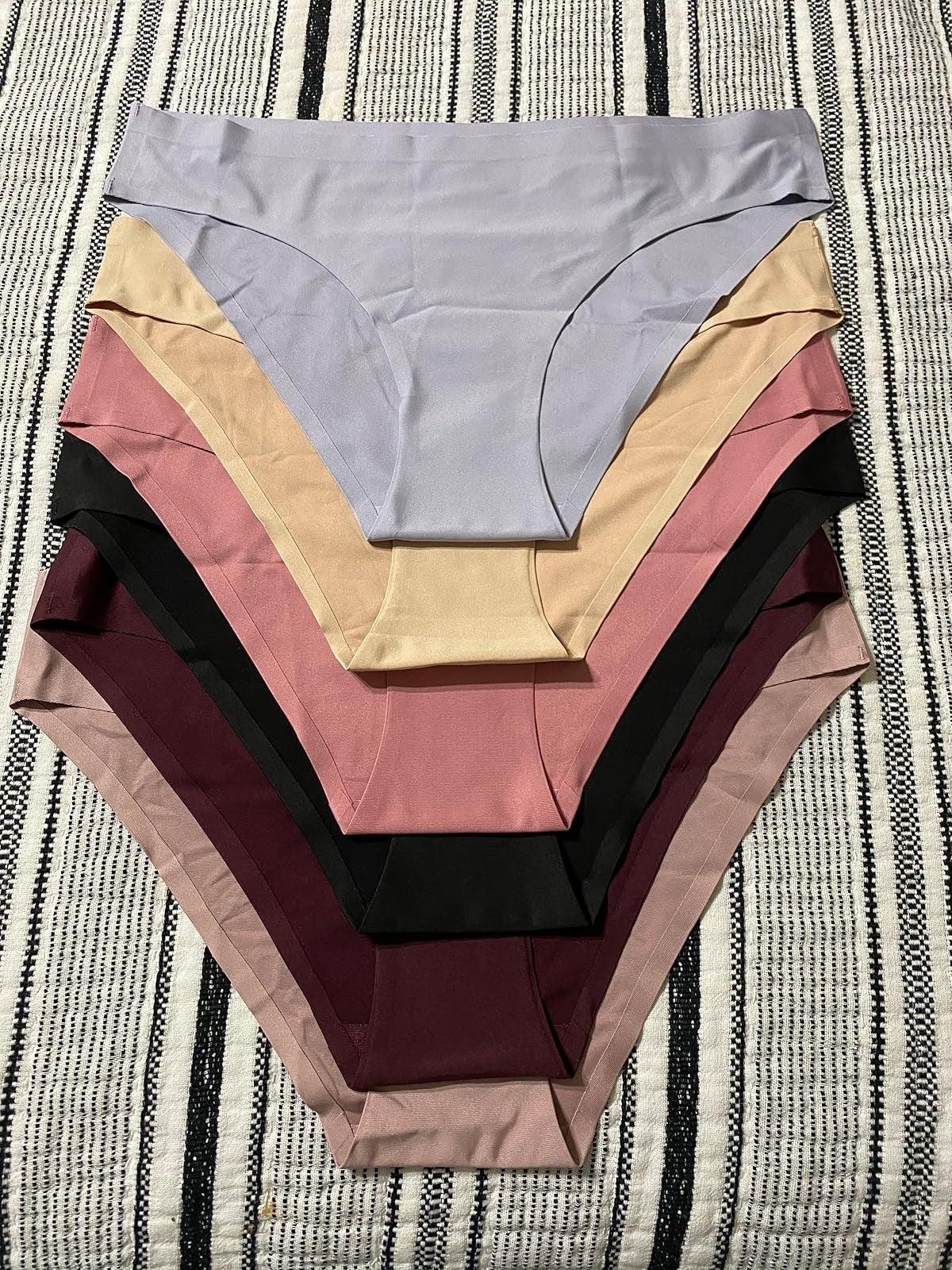 A set of multicolored seamless underwear displayed in a fan-like arrangement on a textured fabric background