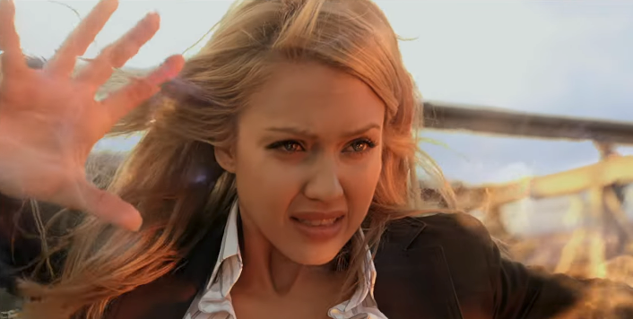 jessica alba with long hair looks determined and raises hands defensively, as if bracing against unseen force, outdoors with blurred background