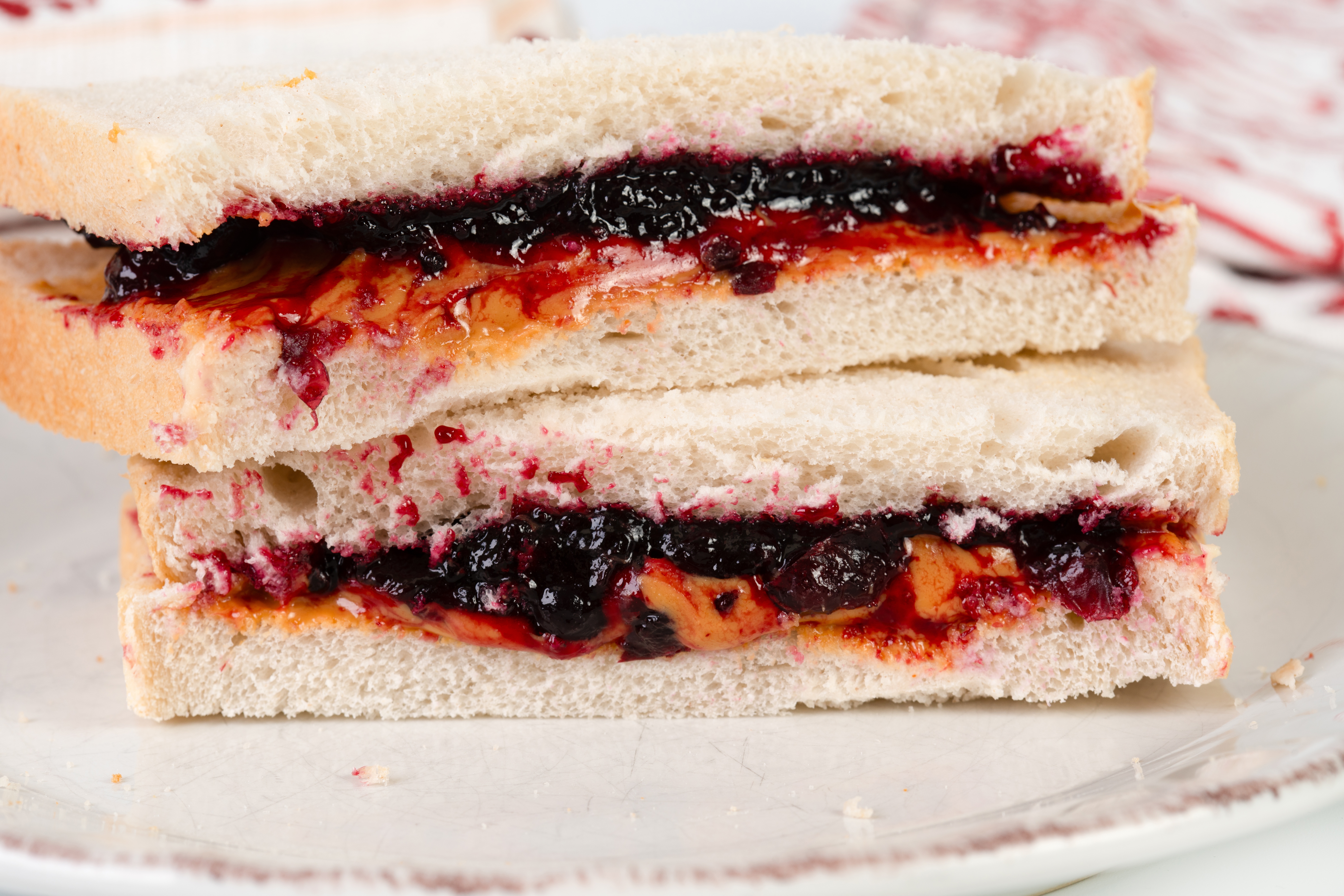 Close-up of a peanut butter and jelly sandwich on a plate, sliced in half