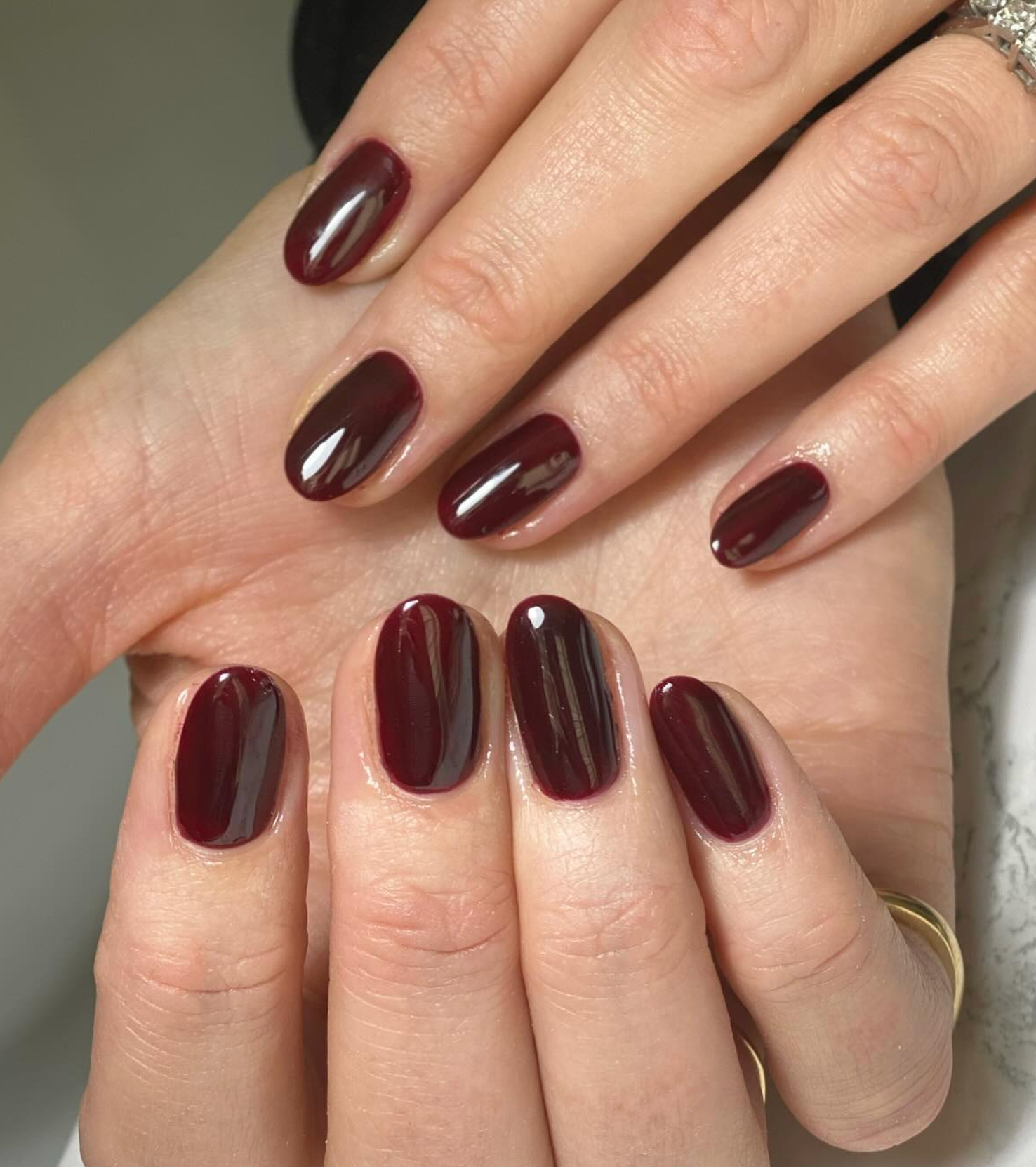 Primer plano de manos con uñas pintadas de borgoña, mostrando un manicure elegante y sencillo