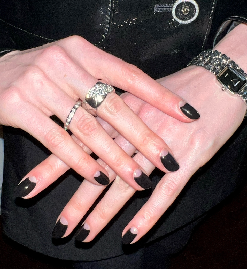 Manos cruzadas con manicura en estilo francés moderno, anillos plateados y reloj metálico