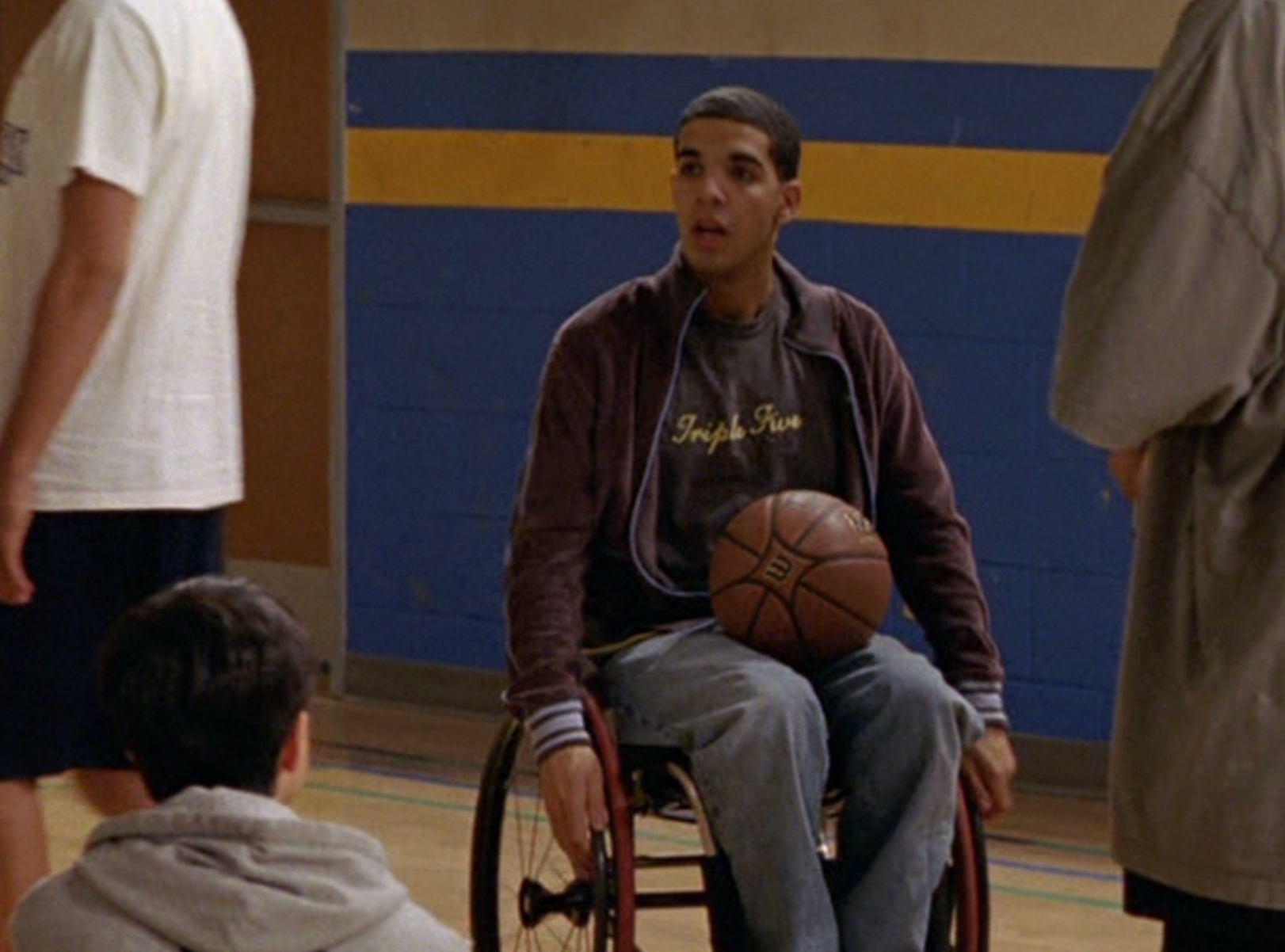 Person i rullestol som holder en basketball i et treningsstudio, fra en TV-serie