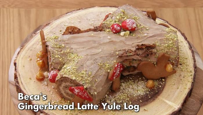 Gingerbread latte Yule log decorated with cherries and crushed nuts on a wooden platter. Text reads "Beca's Gingerbread Latte Yule Log."