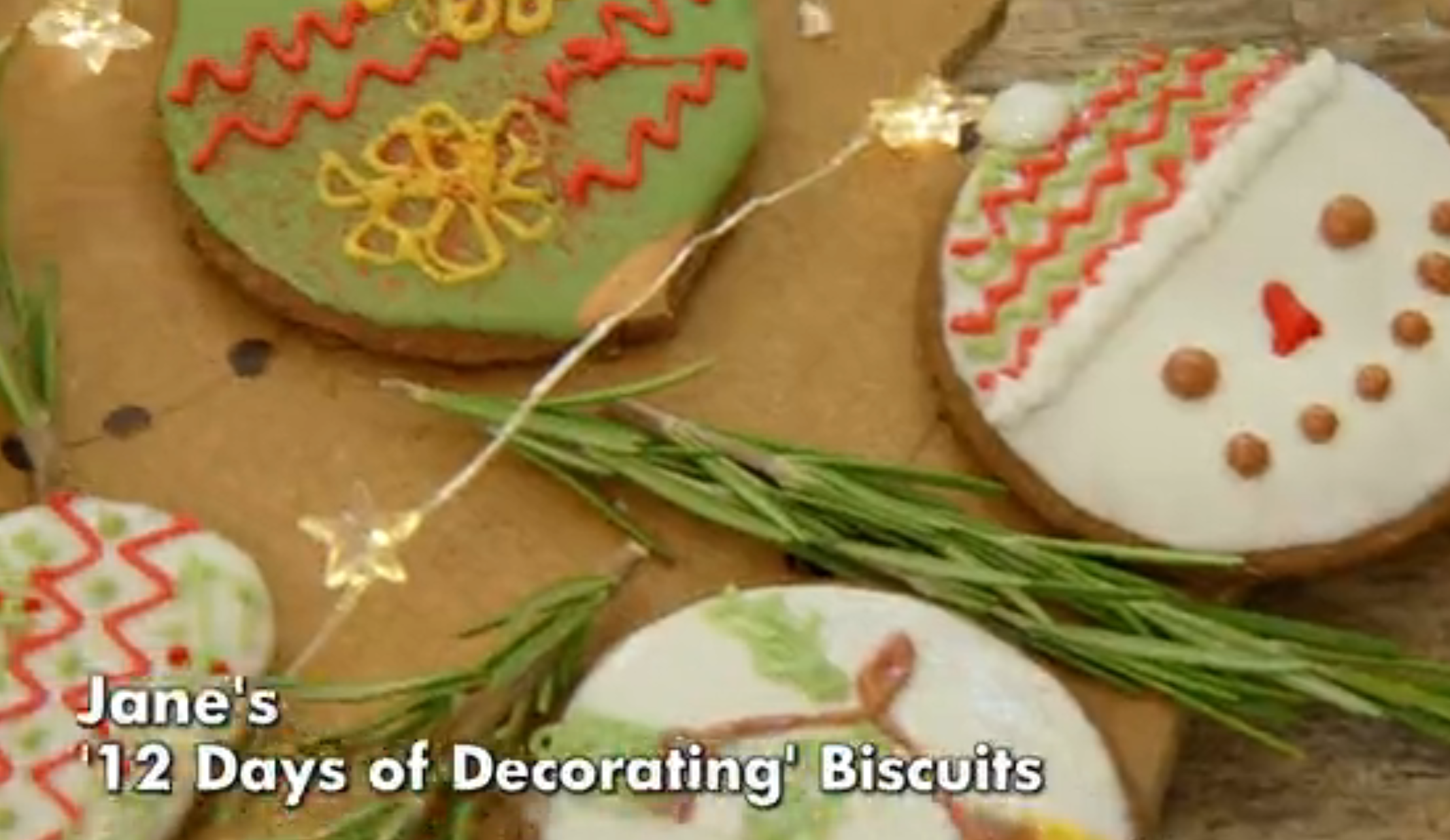 Decorated holiday cookies with icing designs and sprigs of rosemary; text at bottom reads "Jane's '12 Days of Decorating' Biscuits."