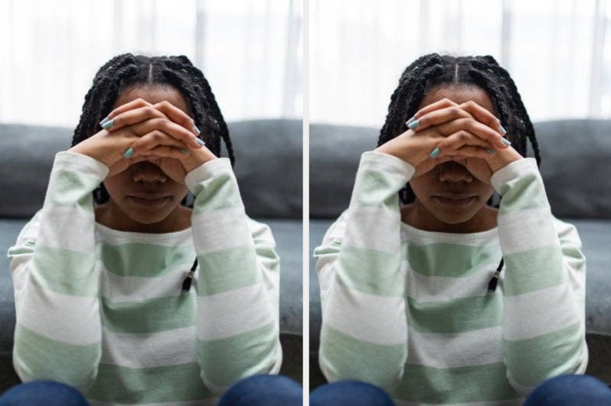 Person sitting on a couch, hands clasped over face, wearing a striped sweater