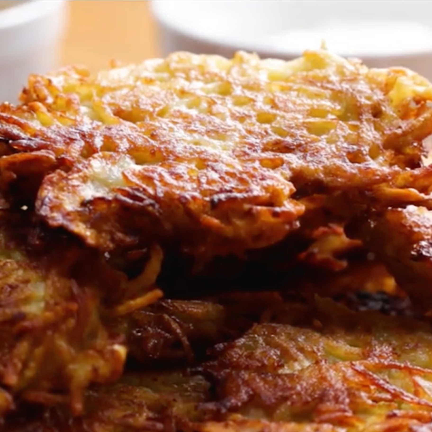 A plate of crispy, golden-brown hash browns piled on top of each other, showcasing their crunchy texture