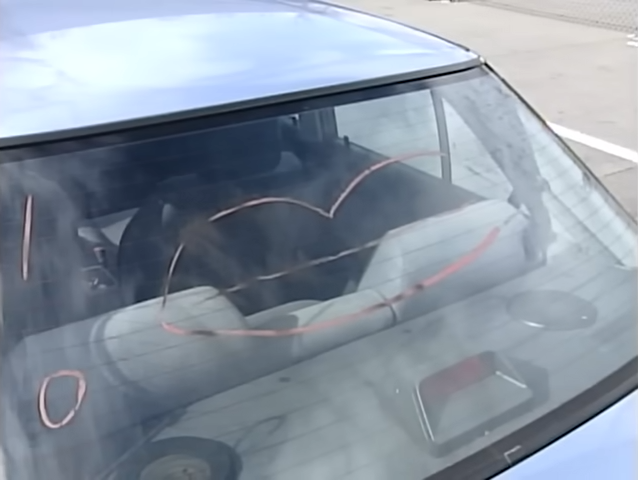 En bils bakrute viser et falmet hjerte som tegner på den, sett fra utsiden