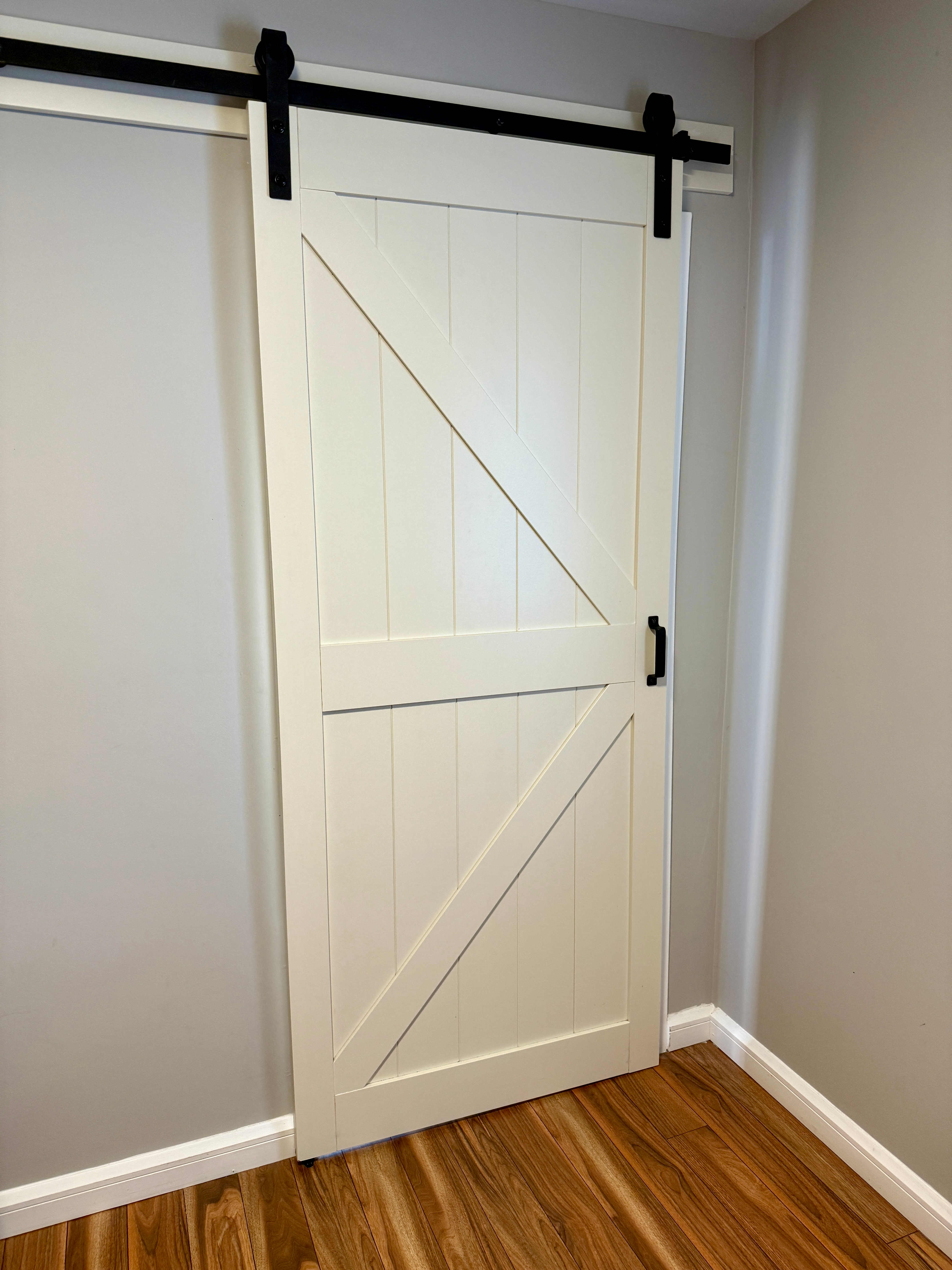 A woody  barn doorway  with a diagonal brace sliding connected  a achromatic  metallic  way   successful  a country   with hardwood flooring