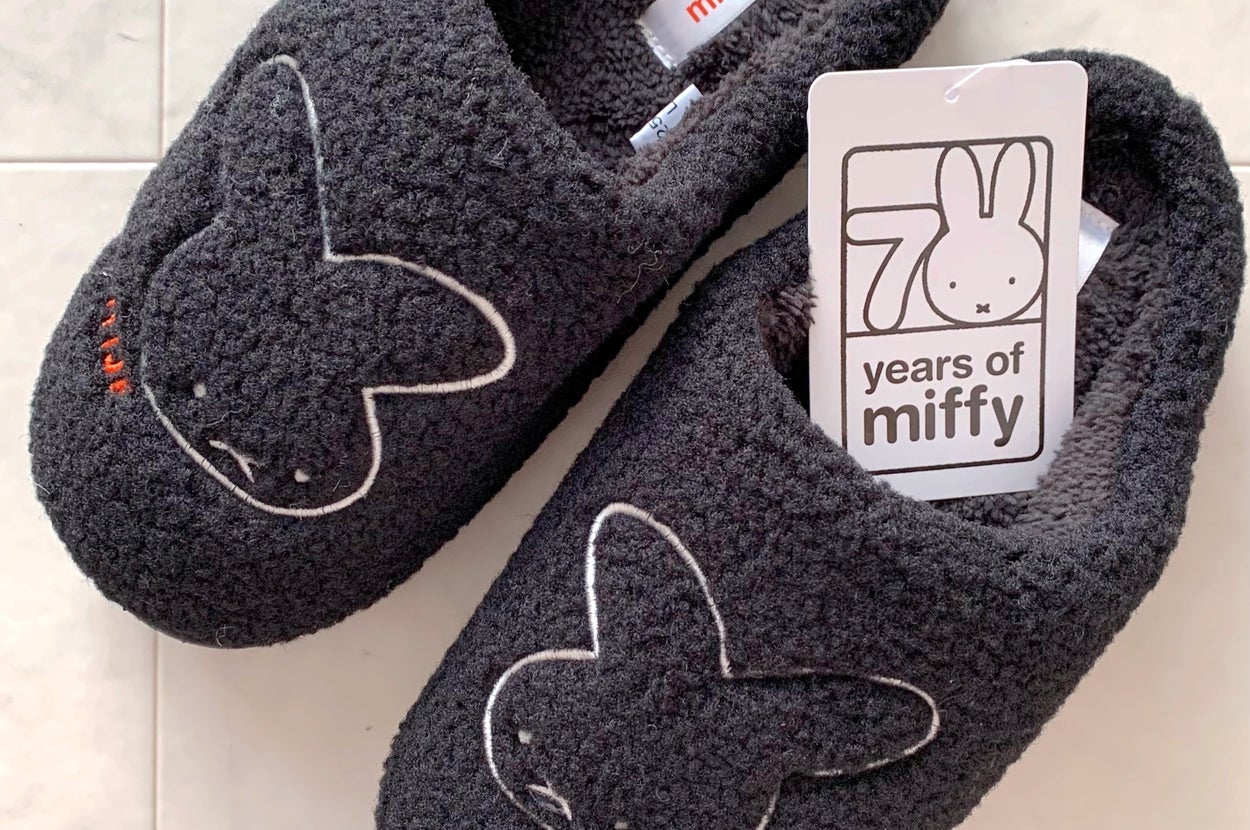 ミッフィーの70周年を祝うロゴタグがついた、ミッフィーの顔がデザインされた黒いスリッパ。