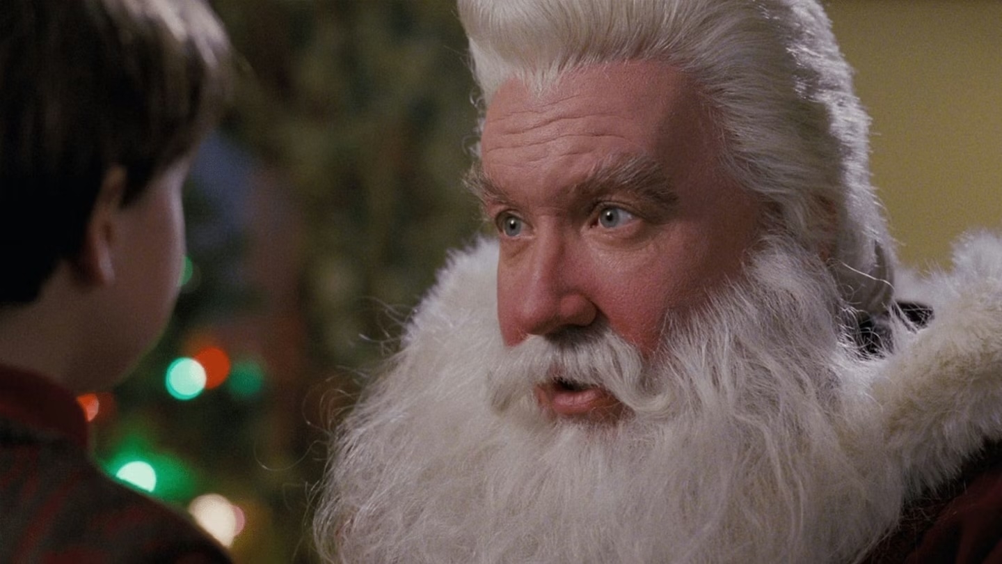 Man dressed arsenic  Santa with fluffy achromatic  beard talks to a kid  indoors, festive decor blurred successful  the background
