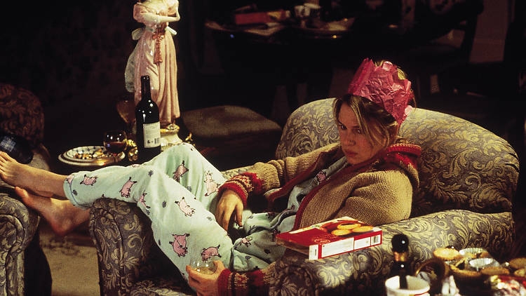 Person relaxing connected  an armchair, wearing pajamas and a insubstantial  crown, holding a drink. A container  of snacks is connected  their lap