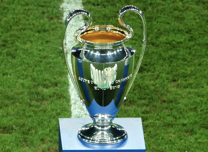 The UEFA Champions League trophy on a pedestal on a soccer field