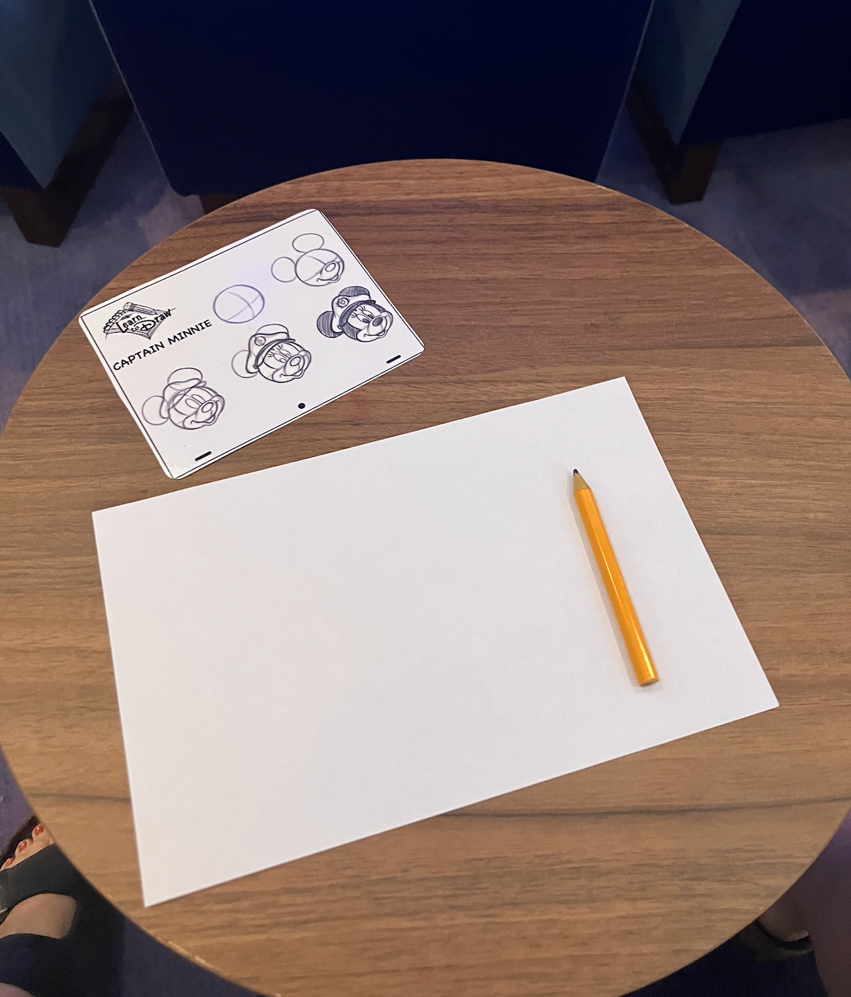 Table with a achromatic  insubstantial  and pencil. To the side, a drafting  usher  labeled "Captain Mickey" shows steps for sketching a character