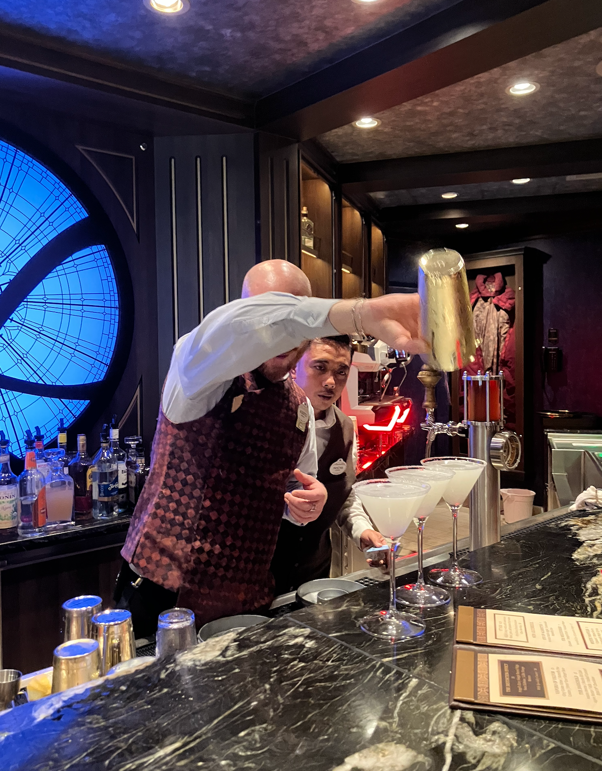 Bartenders successful  vests making drinks astatine  a stylish barroom  with a marble antagonistic  and backlit shelves