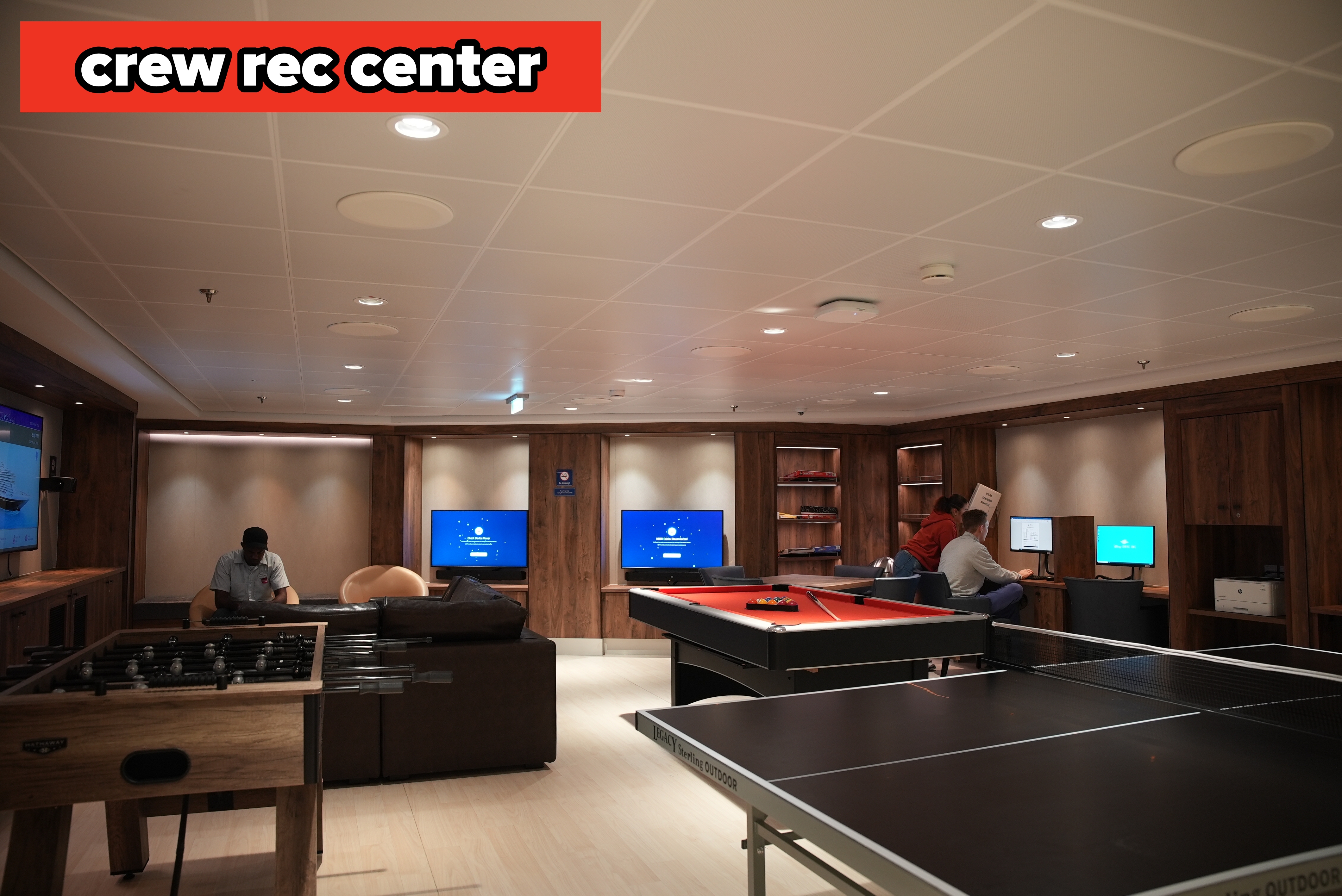A lounge country  with couches, a foosball table, a excavation  table, and radical   utilizing computers