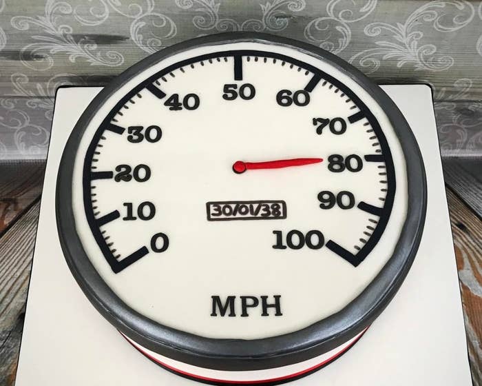 کیک گرد به شکل سرعت‌سنج با سوزن روی ۸۰ مایل در ساعت و تاریخ "30/07/38" در مرکز