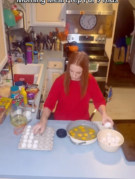 Person in a kitchen cracks eggs into a large bowl, preparing a meal, with various ingredients on the counter