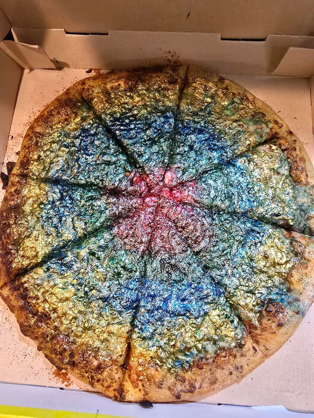 پیتزایی با تاپینگ درخشان و رنگین‌کمان در داخل یک جعبهٔ پیتزا