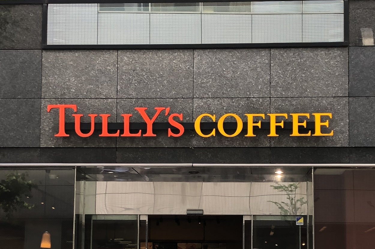 タリーズコーヒーの店舗看板。上部に大きな窓ガラスが見えるビルの外観。