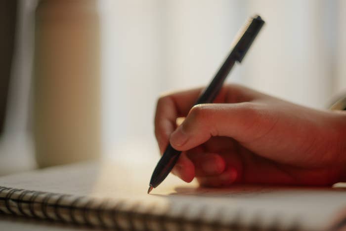 A hand writing with a pen on a notebook, suggesting focus and creativity