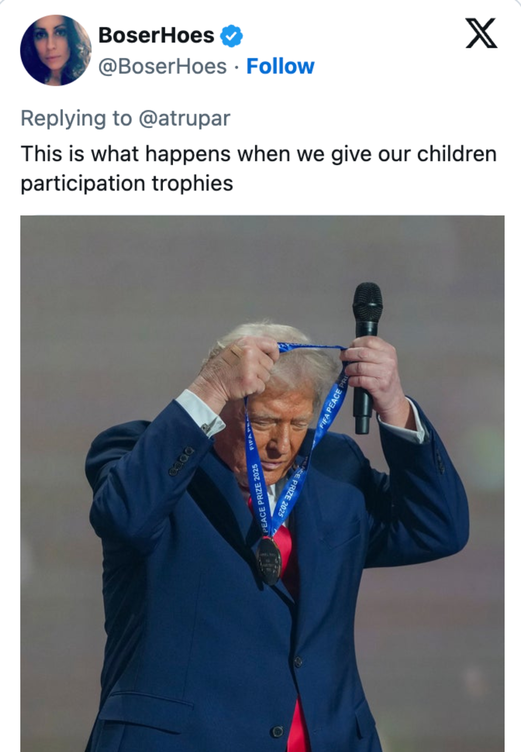 Mann iført dress og slips, smilende, med en medalje rundt halsen. Bildetekst refererer til deltakertrofeer