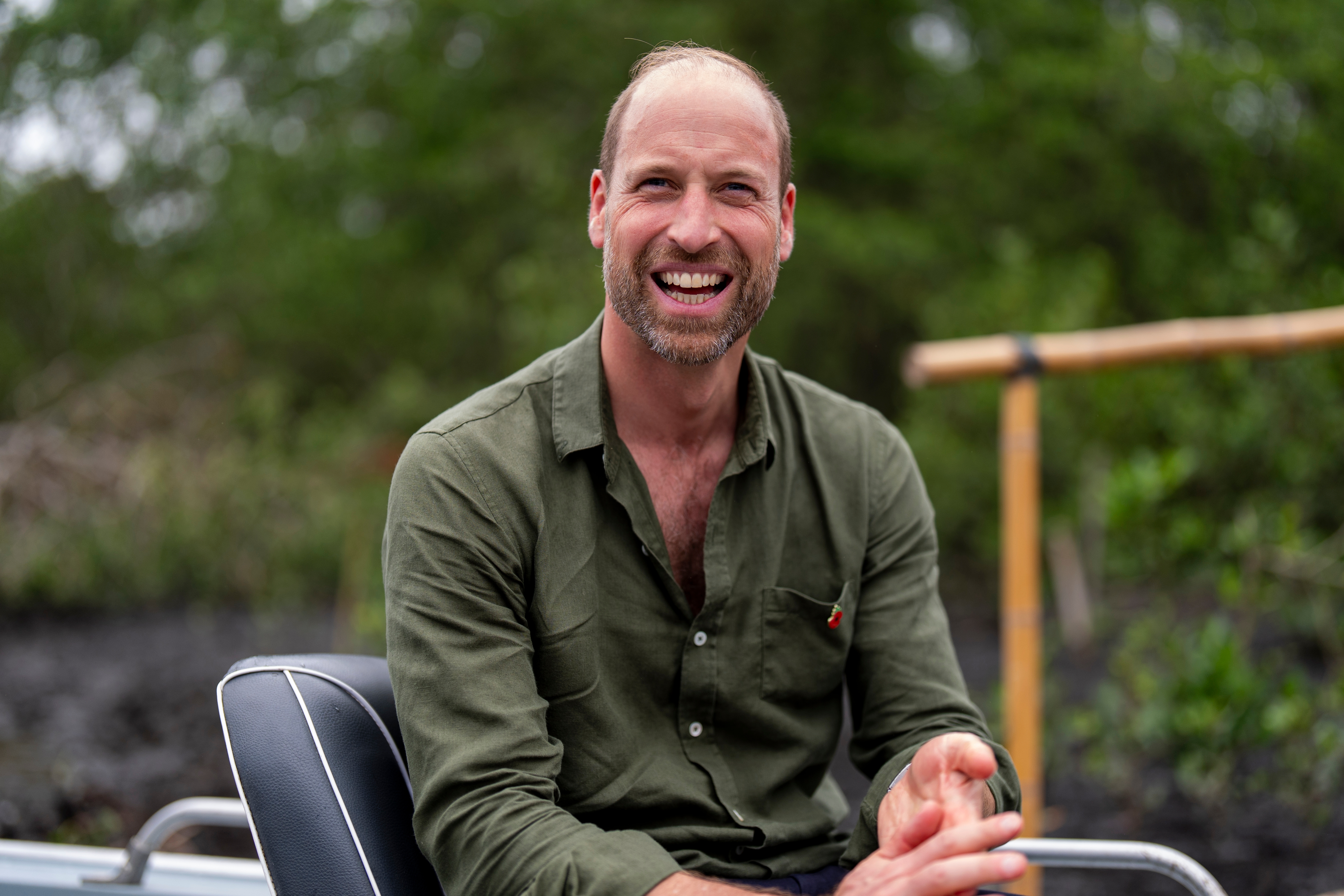 Person outdoors successful  a earthy  setting, smiling portion    seated. Wearing a casual long-sleeve shirt, sleeves partially rolled up