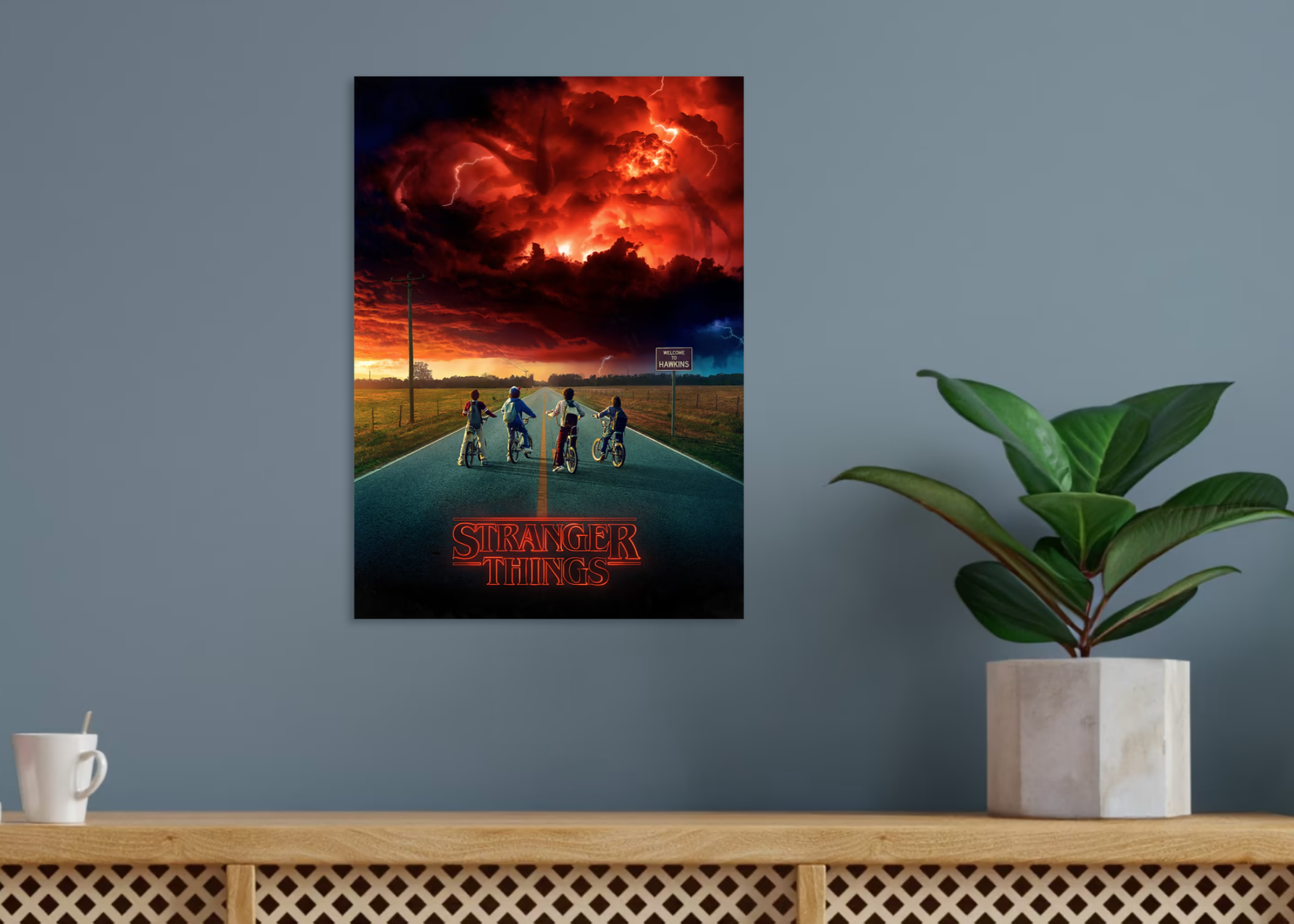 &quot;Stranger Things poster connected  a grey  partition  supra  a support  with a works  and mug, featuring kids connected  bikes beneath   a swirling sky.&quot;