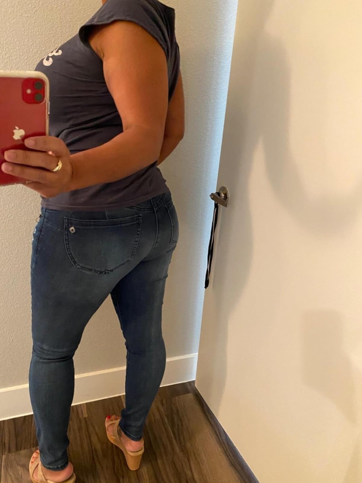 Person wearing a fitted T-shirt and skinny jeans takes a reflector  selfie from down  successful  a fitting room, showcasing the jeans' fit