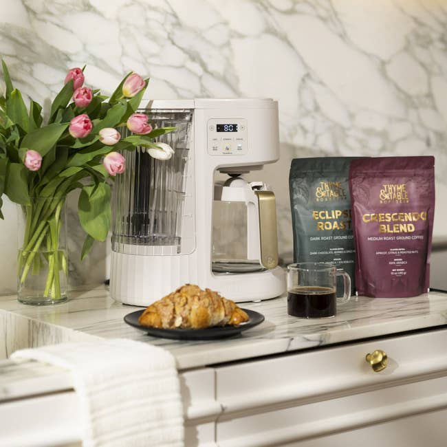 Coffee shaper connected a marble antagonistic with croissants, tulips, a mug, and bags of