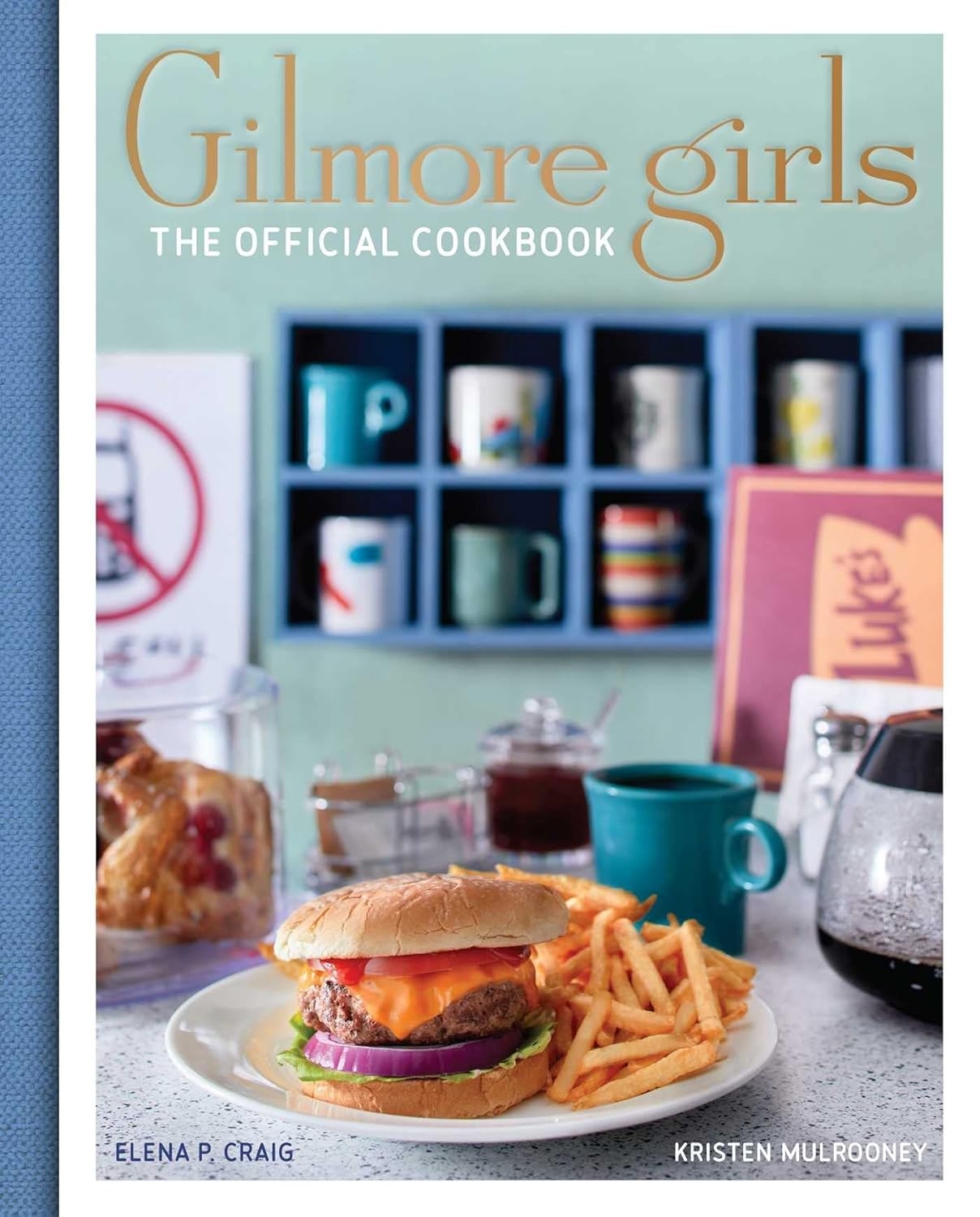  The Official Cookbook&quot; featuring a burger and fries connected  a table, with mugs and baked goods successful  the background
