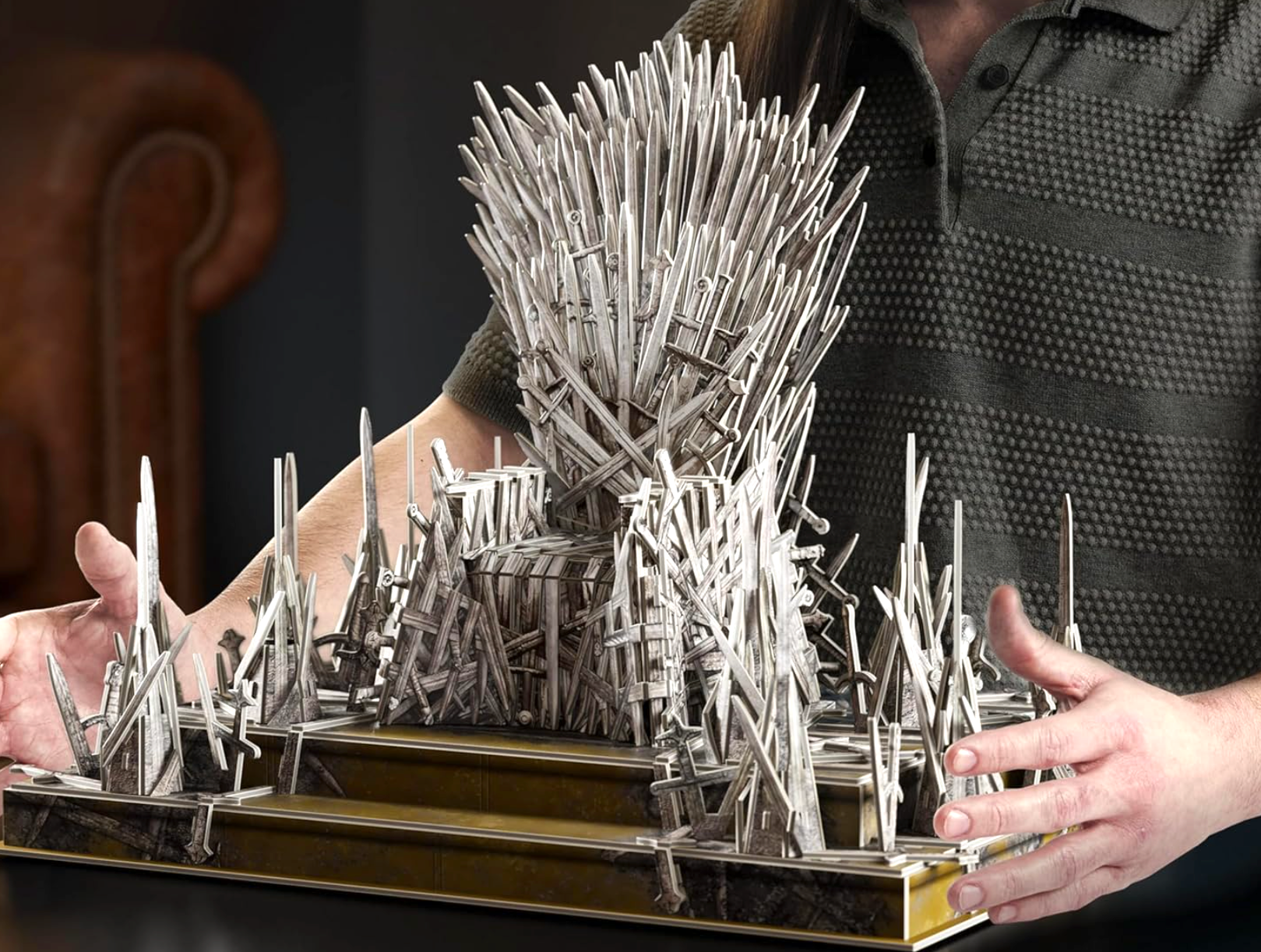 Person holding a miniature exemplary  of a throne made from intricate sword designs, resembling a celebrated  phantasy  amusement   prop