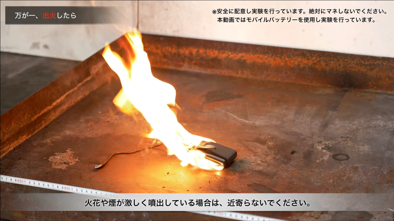 スマートフォンが炎上している写真。注意：安全に配慮し実験を行っています。