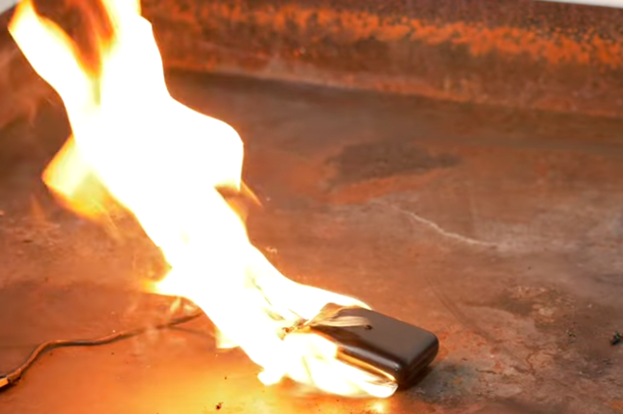 スマートフォンが炎上している写真。注意：安全に配慮し実験を行っています。