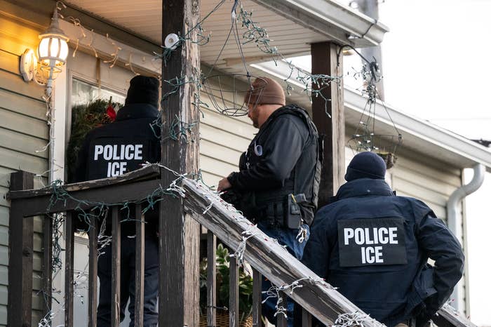 Three ICE officers basal   connected  a home's porch, wearing jackets labeled "Police ICE," appearing to behaviour   authoritative  business