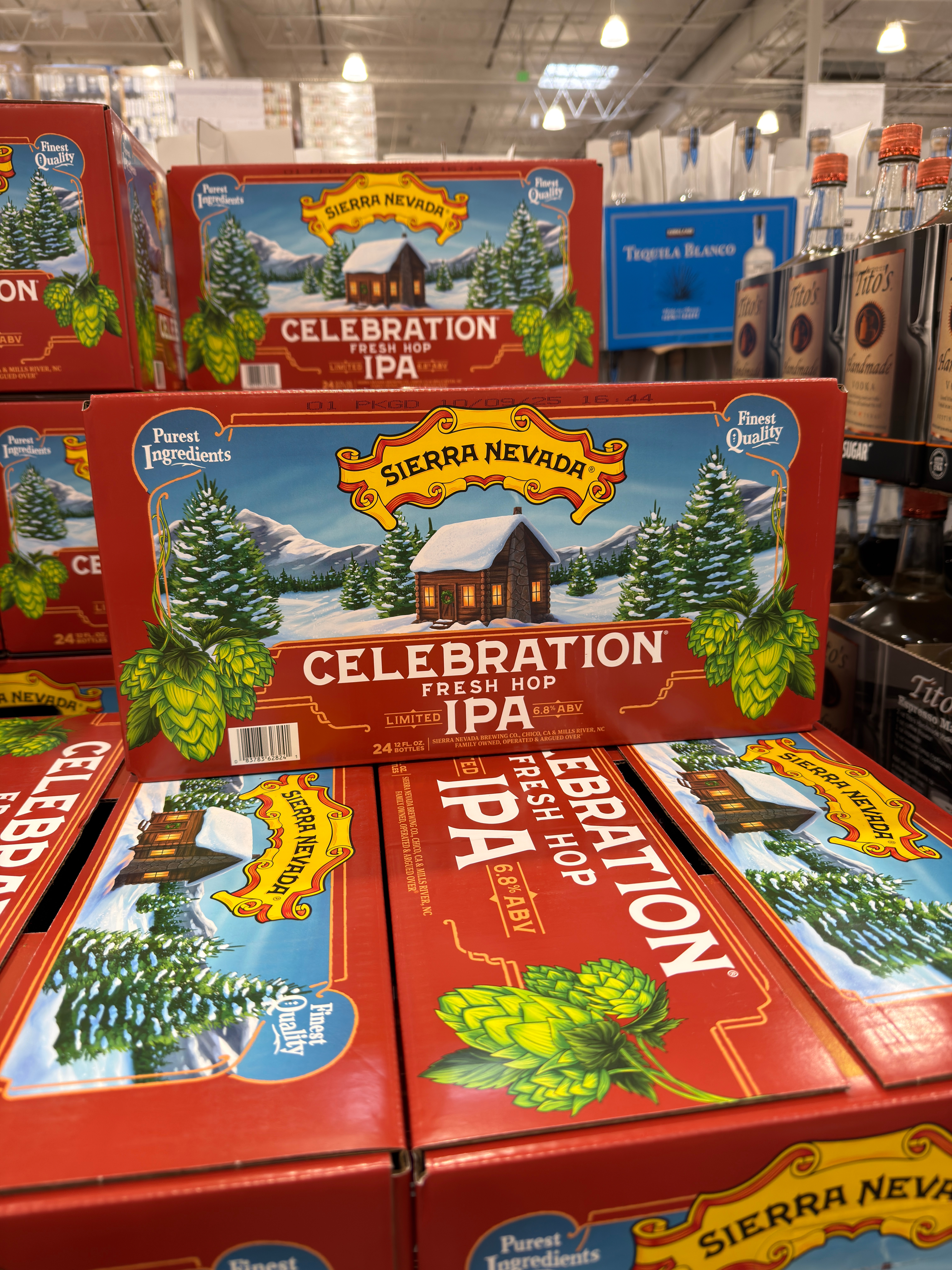 Boxes of Sierra Nevada Celebration Fresh Hop IPA are stacked in a store aisle, surrounded by other alcoholic beverages