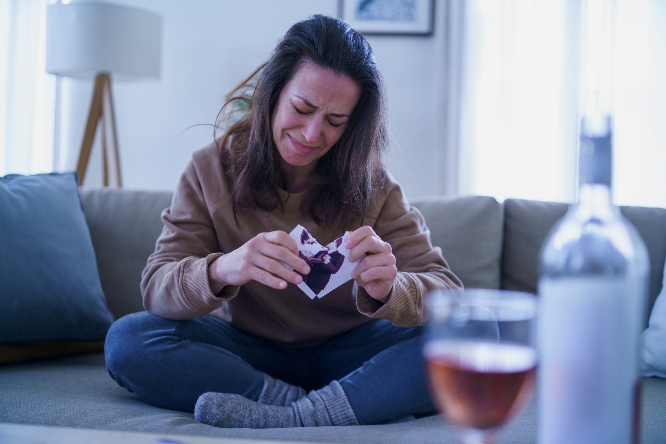 Person connected  a sofa  tearing a photo, appearing emotional. A vino  vessel  and solid  are connected  the array  successful  front
