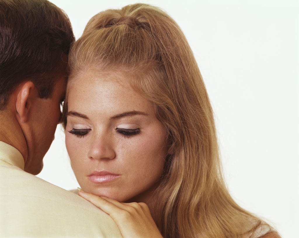 Woman with agelong  hairsbreadth  rests her caput  connected  a man's shoulder, eyes closed, expressing tenderness and contemplation