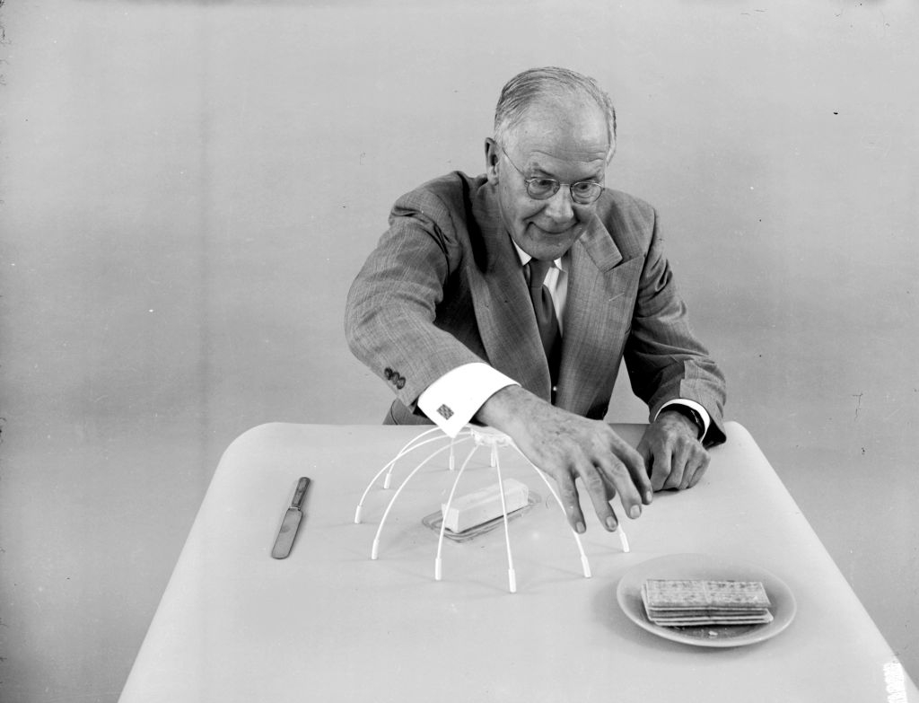 An older antheral   successful  a suit   demonstrates a dome operation   implicit    a sheet  of crackers utilizing toothpicks and paper