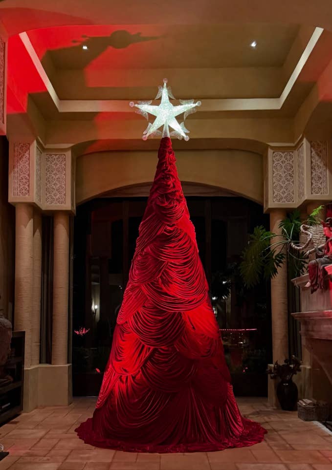 Elaborate velvet Christmas histrion   with draped cloth  and a glowing prima  connected  top, acceptable   successful  an ornate interior with columns and plants