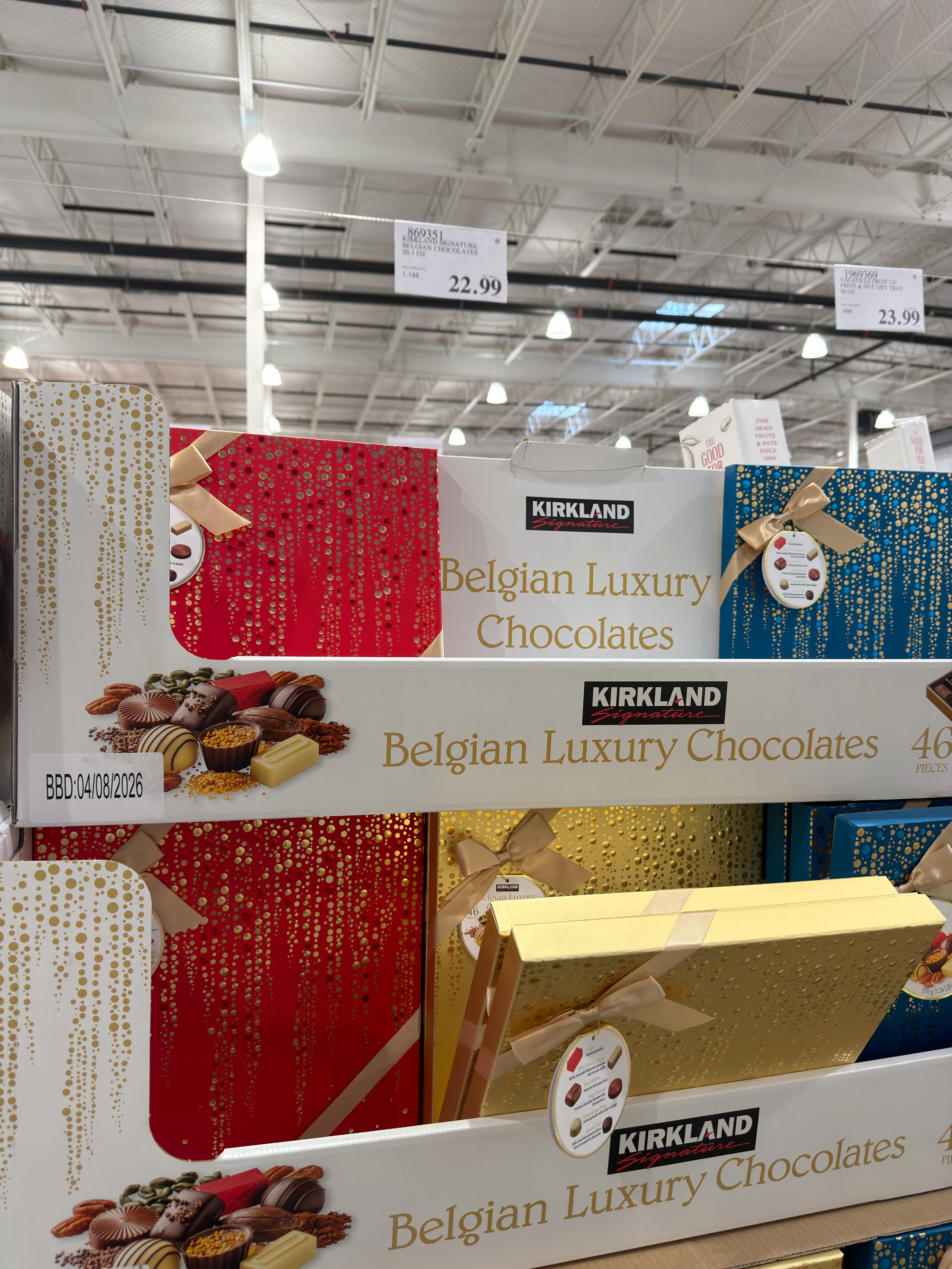 Store display of Kirkland Belgian Luxury Chocolates in shiny, decorated boxes with price labels above