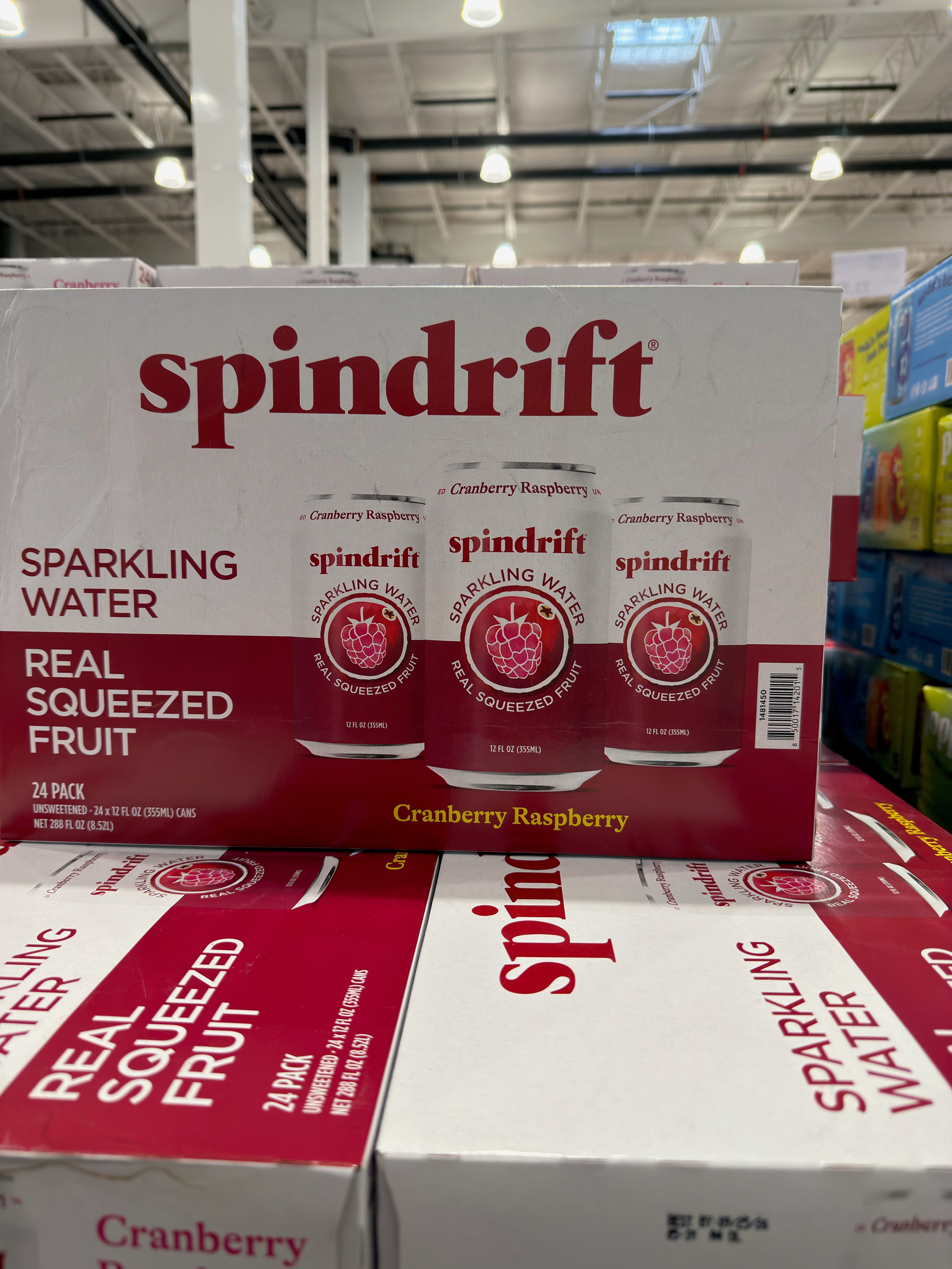 Spindrift sparkling water display in a store, featuring 24-pack boxes of Cranberry Raspberry flavor with real squeezed fruit