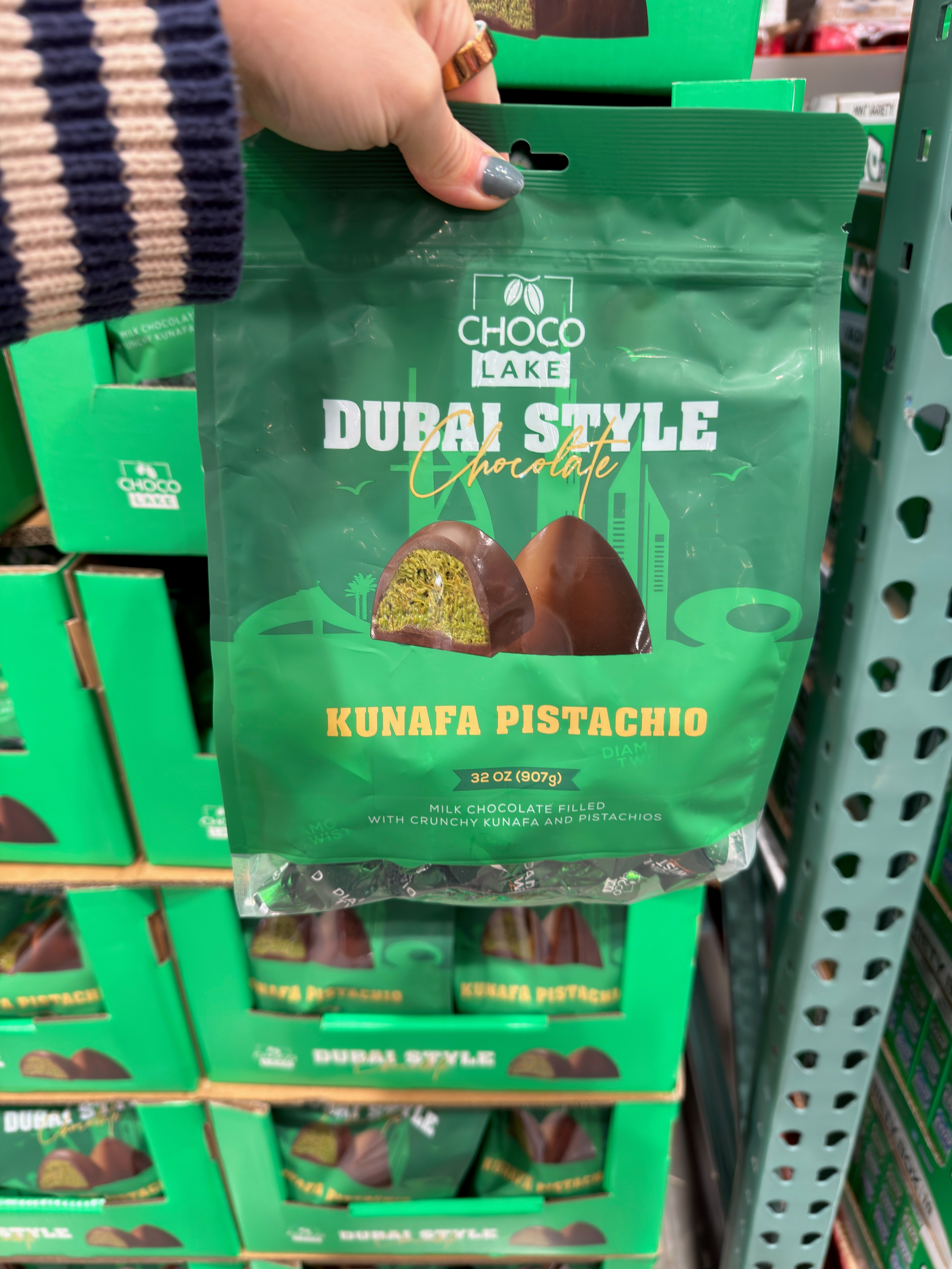 A hand holds a bag of Choco Lake Dubai Style Chocolate, labeled "Kunafa Pistachio," with milk chocolate and crunchy kunafa pistachio filling