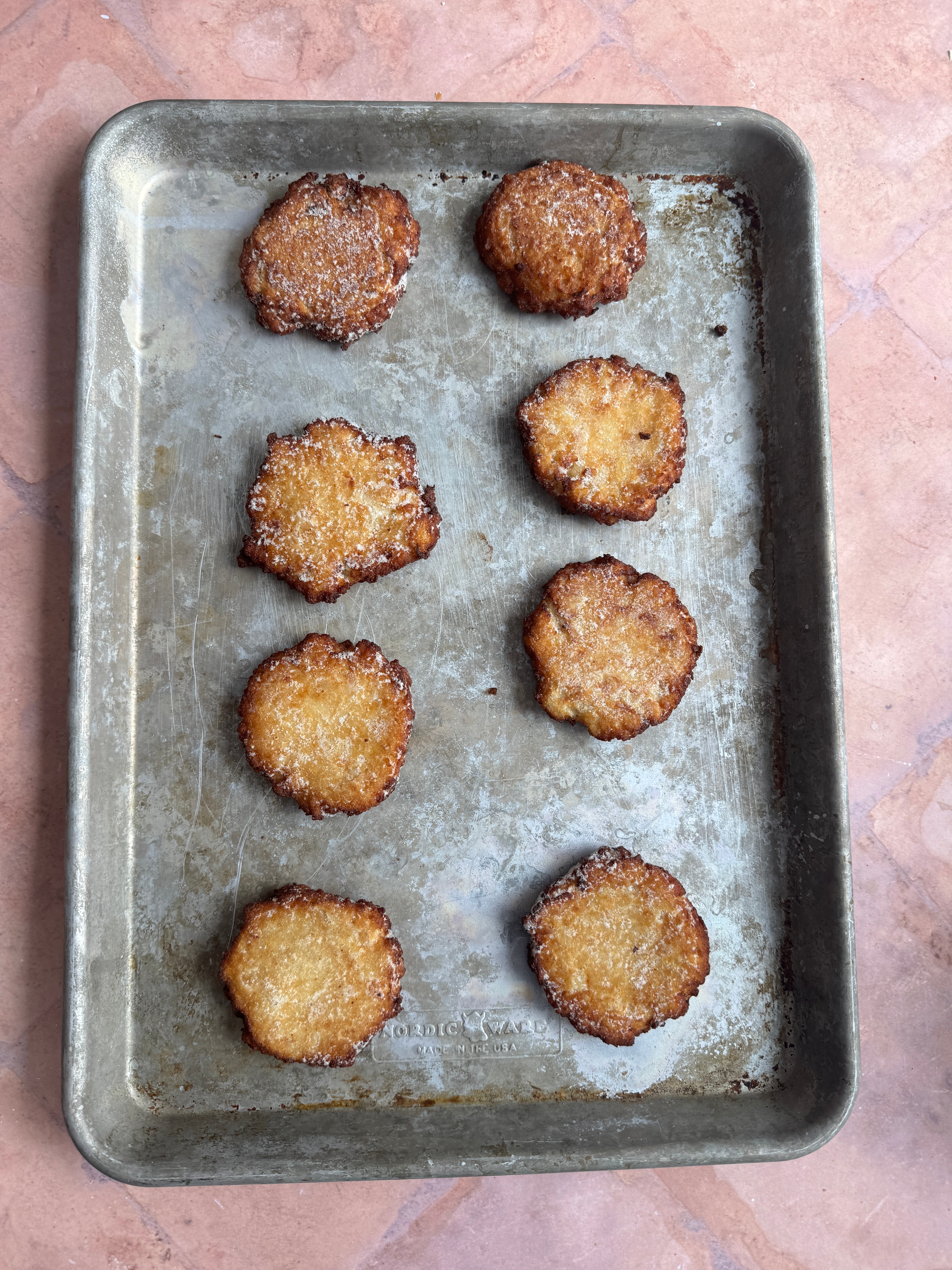 Eight frozen latkes on a metal baking tray