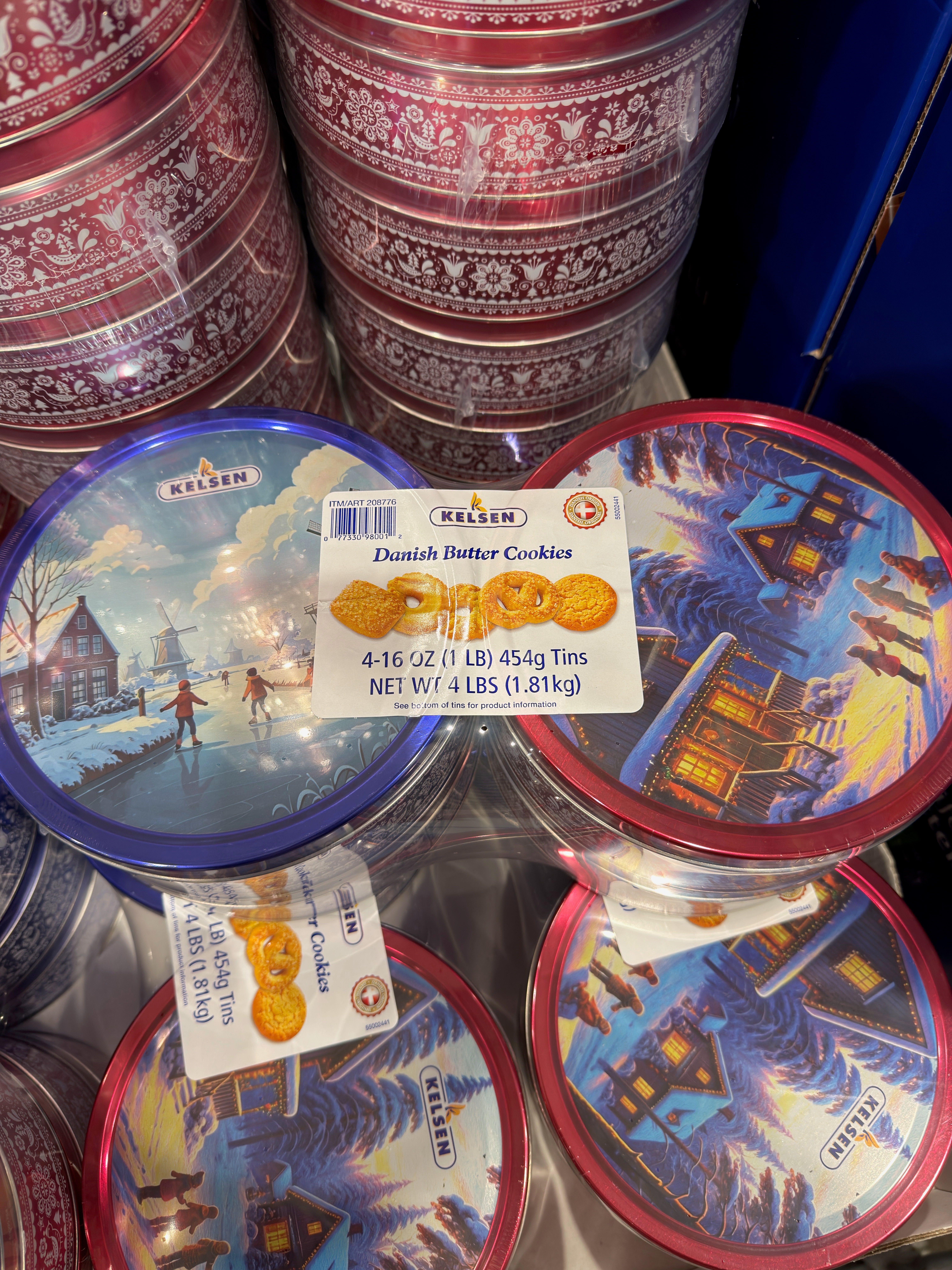 Danish butter cookies in decorative tins featuring winter scenes. Each tin holds 1 lb of cookies, with a display of multiple tins stacked