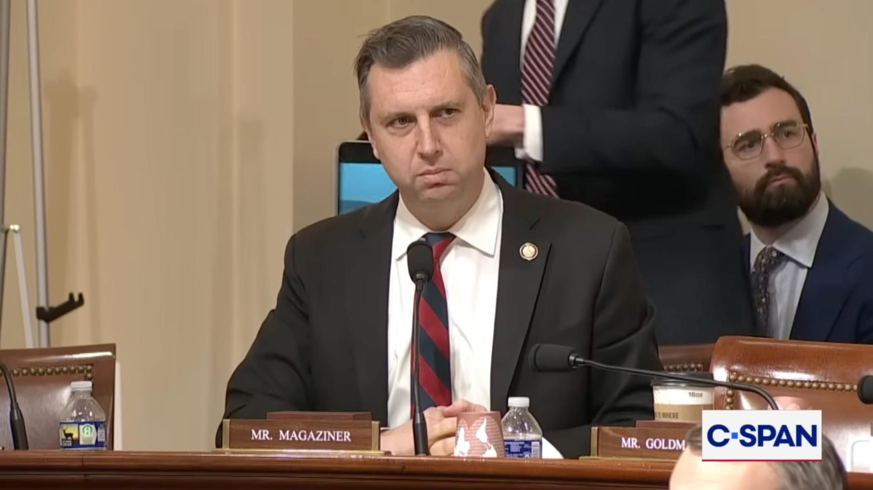 En mann sitter ved et høringsbord i kongressen, iført dress og stripet slips. Det er en C-SPAN-logo nederst i høyre hjørne