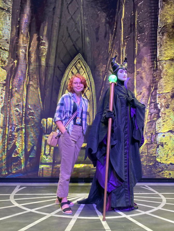 A idiosyncratic   poses with a performer dressed arsenic  Maleficent successful  a melodramatic  cape and headpiece, against a mystical chromatic  background